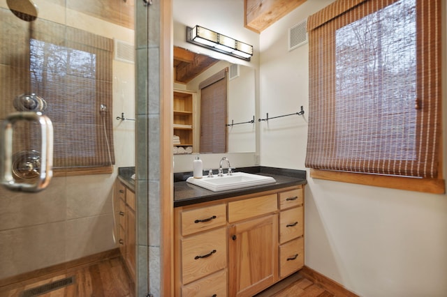 bathroom with vanity, wood finished floors, visible vents, and a shower stall