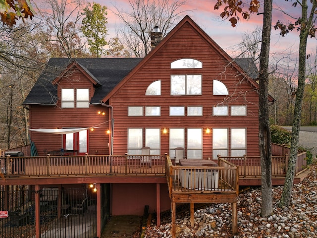 rear view of house featuring a deck, roof with shingles, and a chimney