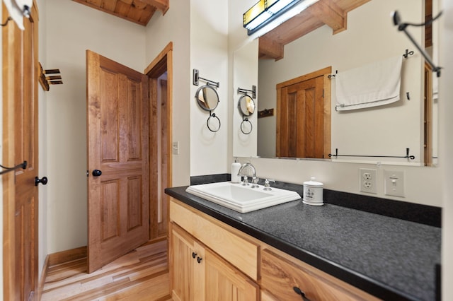 bathroom featuring vanity, beam ceiling, and wood finished floors