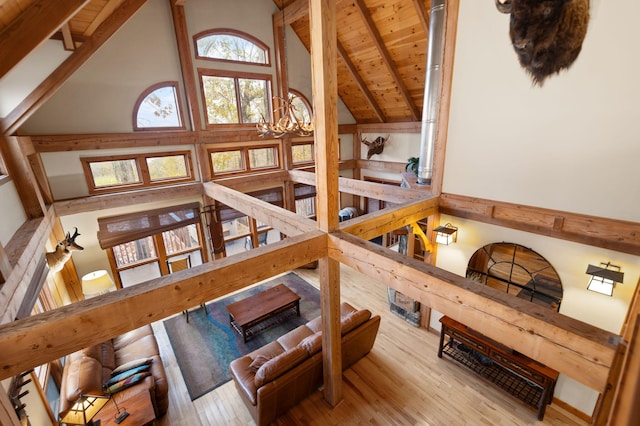 living area with an inviting chandelier, high vaulted ceiling, wood finished floors, and beamed ceiling