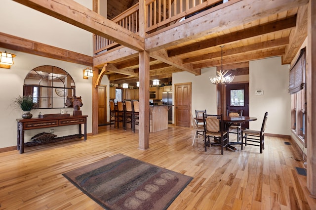 dining space featuring baseboards, light wood finished floors, beamed ceiling, and a notable chandelier