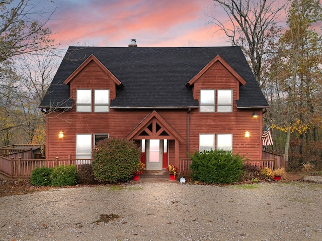 rustic home with a shingled roof, a chimney, and a wooden deck