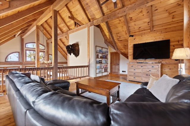 living area with beam ceiling, wood ceiling, wood walls, wood finished floors, and high vaulted ceiling