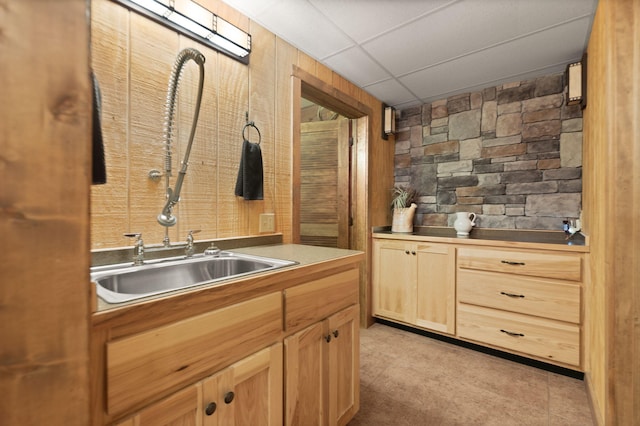 kitchen featuring a paneled ceiling, light brown cabinets, and a sink