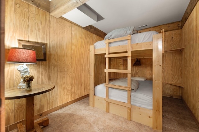 unfurnished bedroom featuring wood walls, a skylight, and visible vents