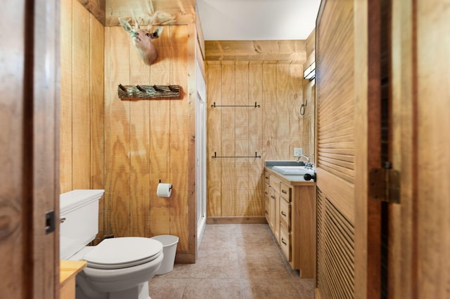 full bathroom featuring tile patterned flooring, toilet, wooden walls, vanity, and a shower stall