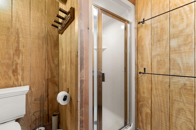 bathroom featuring wood walls, a shower stall, and toilet