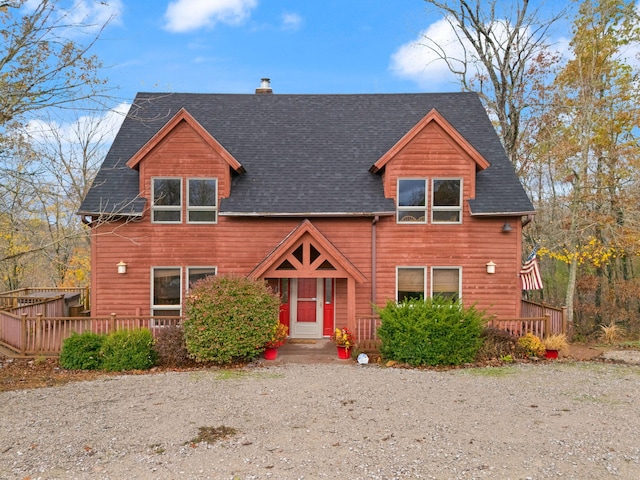 rustic home featuring roof with shingles, a chimney, and a wooden deck