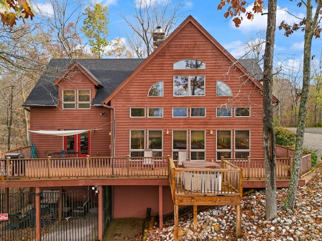 back of property with a deck, roof with shingles, fence, and a chimney