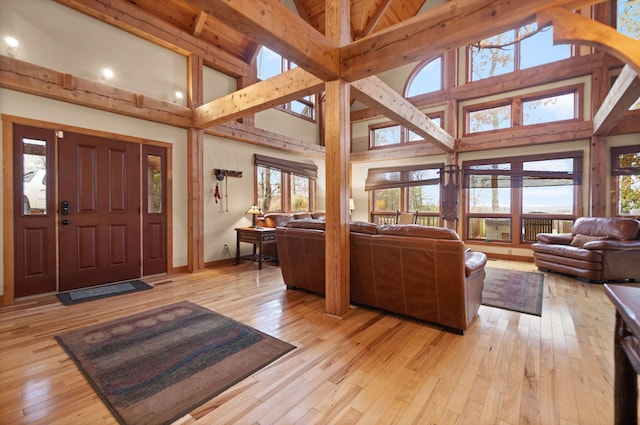 living area with high vaulted ceiling, beamed ceiling, light wood-type flooring, and baseboards