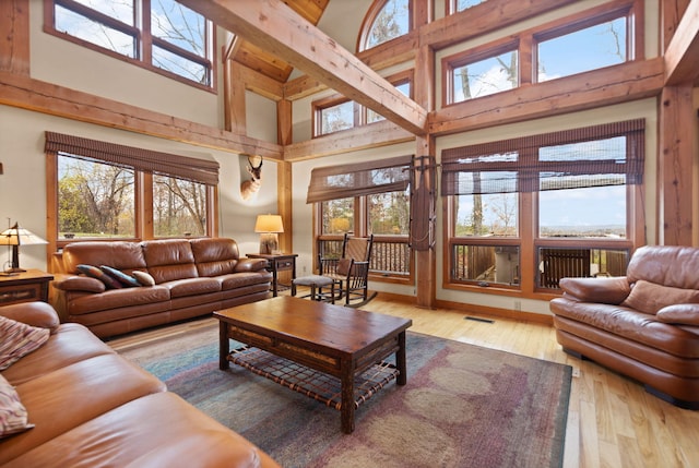 living area featuring a towering ceiling, wood-type flooring, and visible vents