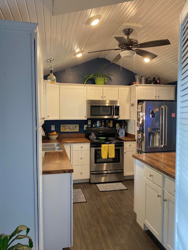 kitchen featuring butcher block countertops, vaulted ceiling, white cabinets, wood ceiling, and appliances with stainless steel finishes