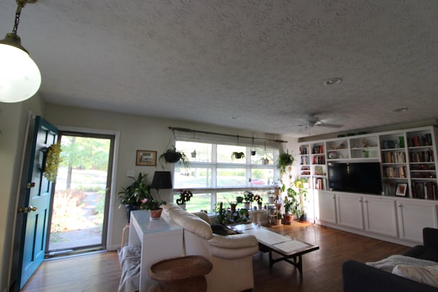 living room with ceiling fan, wood-type flooring, and a textured ceiling