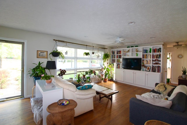 living room featuring a textured ceiling, ceiling fan, and dark wood-type flooring