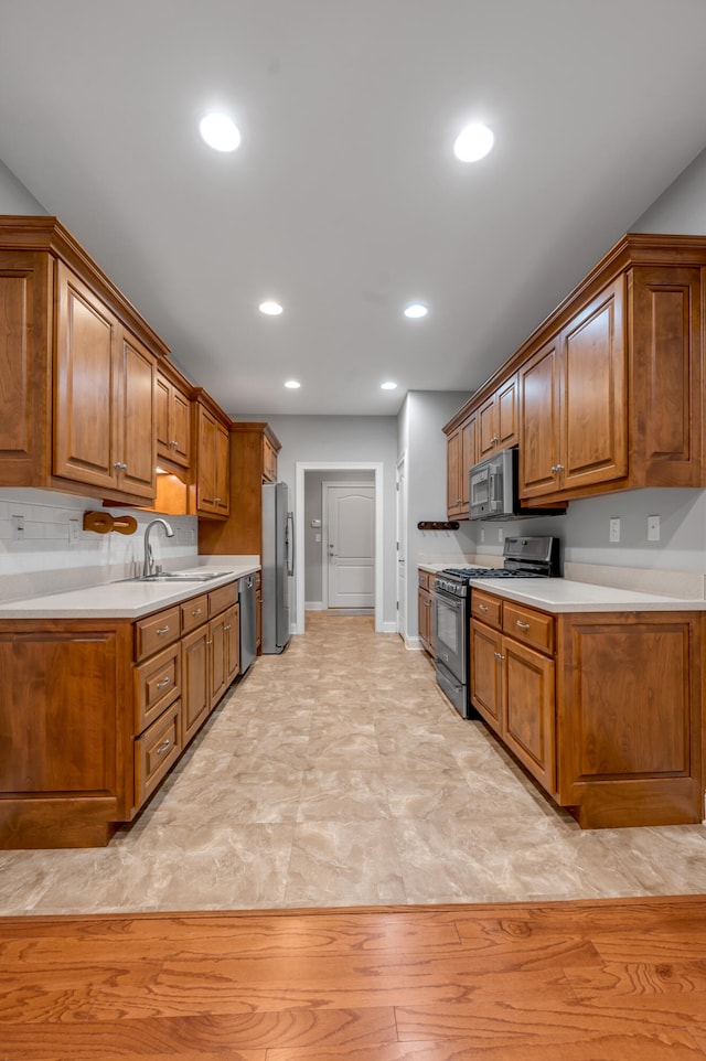 kitchen featuring tasteful backsplash, sink, light hardwood / wood-style flooring, and appliances with stainless steel finishes