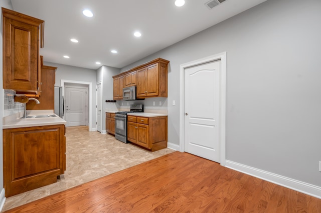 kitchen with stainless steel appliances, light hardwood / wood-style flooring, and sink