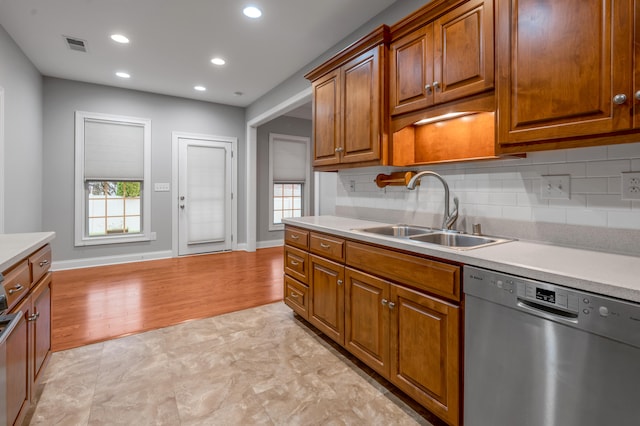 kitchen with dishwasher, light hardwood / wood-style floors, tasteful backsplash, and sink