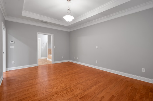 unfurnished room with a raised ceiling, light hardwood / wood-style flooring, and ornamental molding