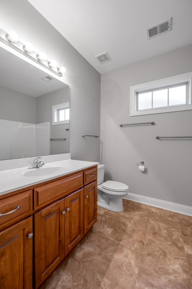 bathroom featuring vanity, a healthy amount of sunlight, and toilet