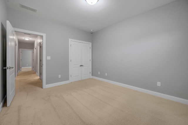 unfurnished bedroom with a closet and light colored carpet