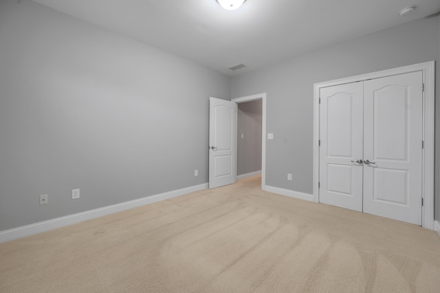 unfurnished bedroom with light carpet and a closet