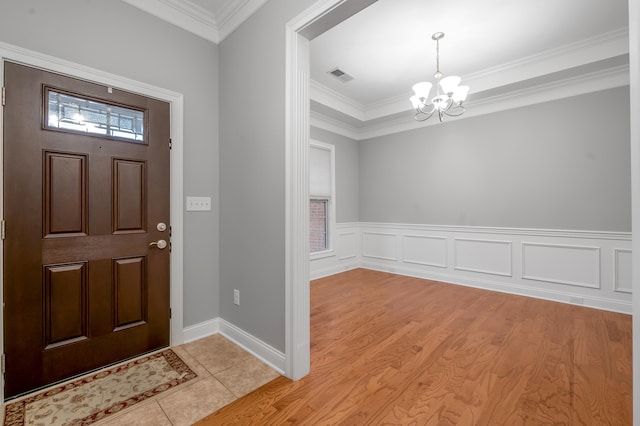 foyer with a notable chandelier, ornamental molding, and light hardwood / wood-style flooring