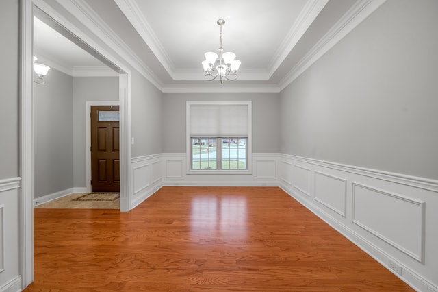 empty room featuring a chandelier, wood-type flooring, and ornamental molding