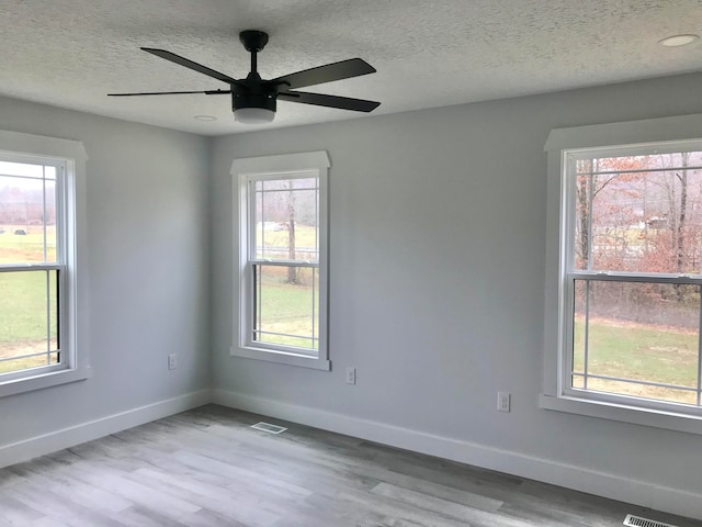 spare room with ceiling fan, light hardwood / wood-style floors, and a textured ceiling