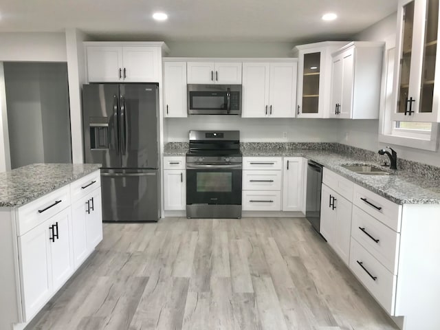 kitchen featuring white cabinets, light stone counters, light wood-type flooring, and appliances with stainless steel finishes