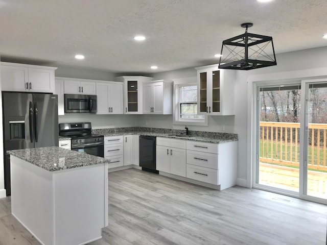 kitchen with white cabinetry, light hardwood / wood-style floors, stone countertops, and appliances with stainless steel finishes