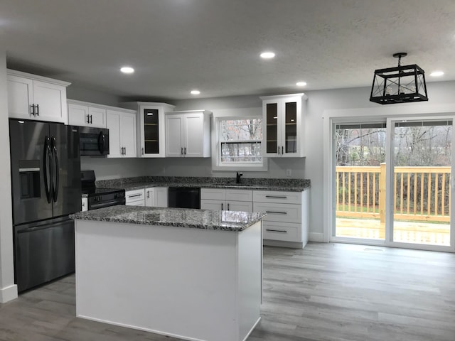 kitchen featuring black appliances, a center island, white cabinetry, and light hardwood / wood-style flooring