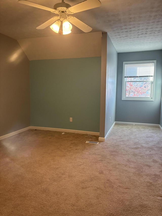 empty room featuring lofted ceiling, baseboards, a ceiling fan, and light colored carpet