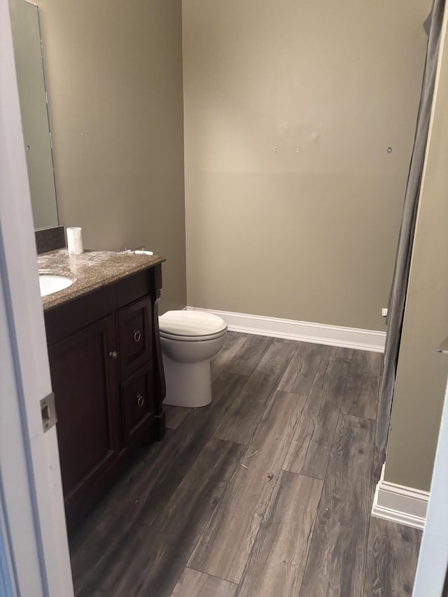 bathroom with vanity, wood finished floors, toilet, and baseboards