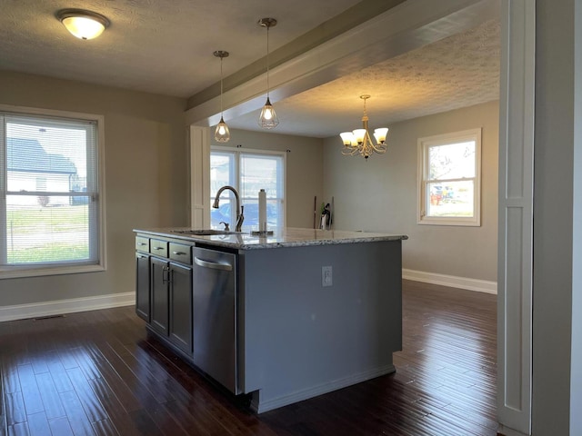 kitchen with dark wood finished floors, decorative light fixtures, light stone countertops, a kitchen island with sink, and stainless steel dishwasher