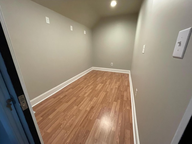 empty room with light wood-type flooring, lofted ceiling, and baseboards