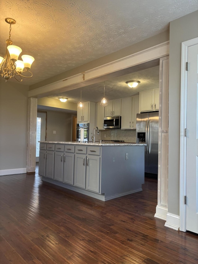 kitchen featuring a textured ceiling, hanging light fixtures, stainless steel appliances, and dark hardwood / wood-style floors