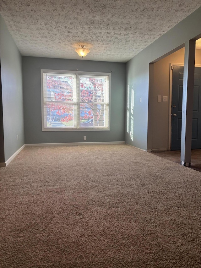 spare room with carpet flooring, a textured ceiling, and baseboards