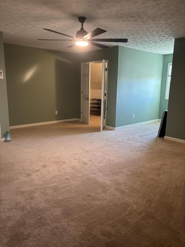 carpeted empty room with a ceiling fan, a textured ceiling, and baseboards