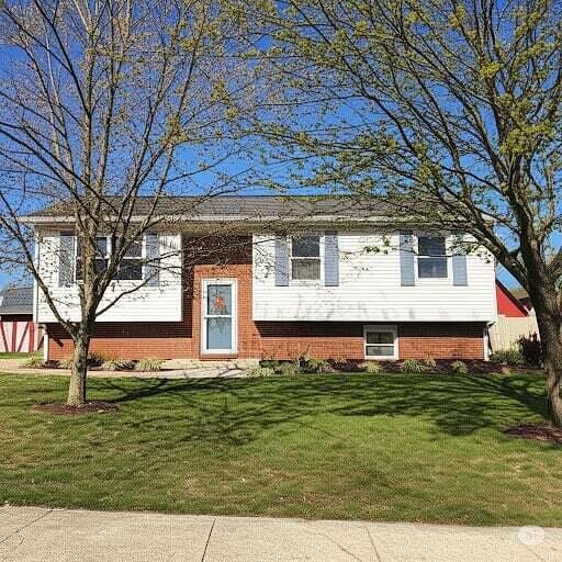 split foyer home featuring a front lawn and brick siding