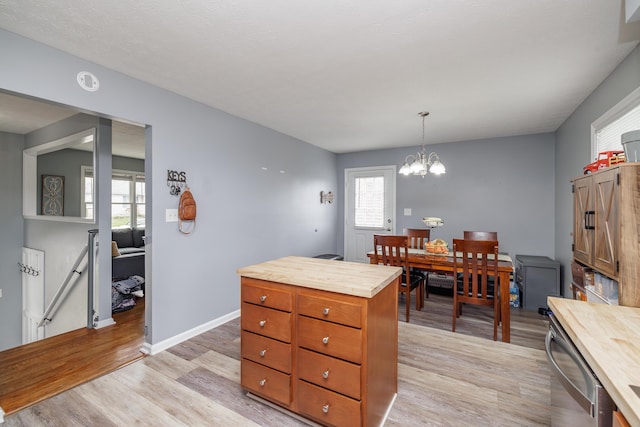 kitchen featuring wooden counters, light wood-type flooring, a chandelier, stainless steel dishwasher, and pendant lighting