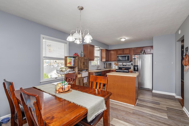 dining room with a chandelier, light wood-type flooring, and baseboards