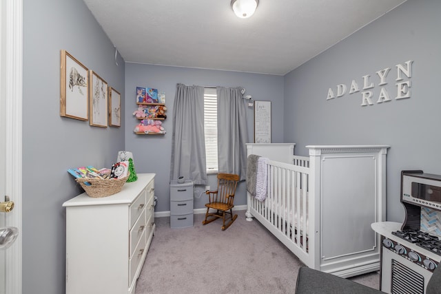 bedroom with light carpet, a nursery area, and baseboards