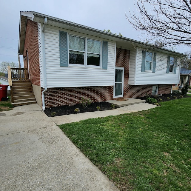 raised ranch featuring a front yard and brick siding
