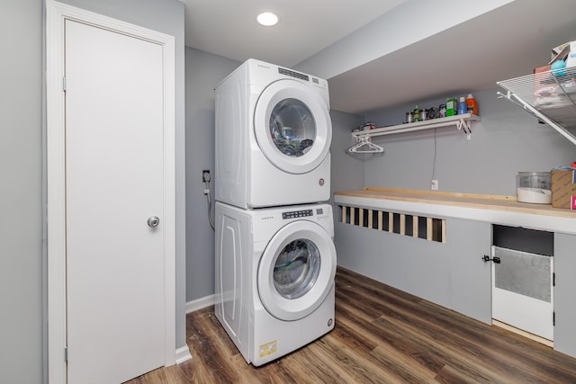 clothes washing area with stacked washing machine and dryer, wood finished floors, baseboards, and recessed lighting