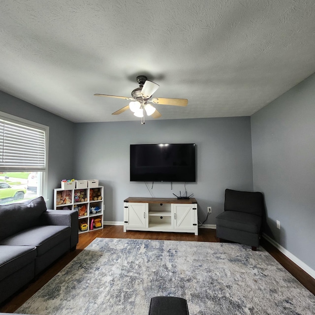living area featuring dark wood-style floors, ceiling fan, baseboards, and a textured ceiling
