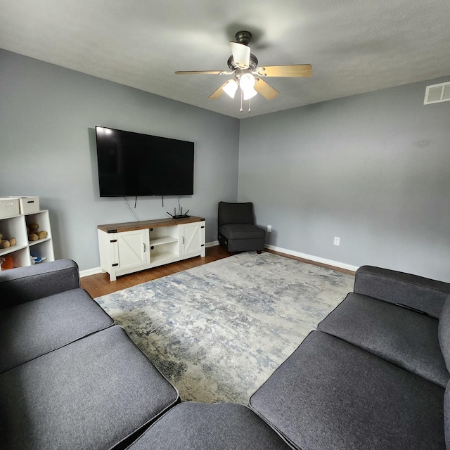 living room with a ceiling fan, baseboards, and dark wood-style flooring