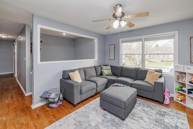 living room featuring wood finished floors, a ceiling fan, and baseboards