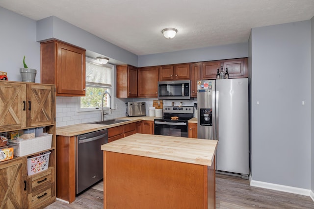 kitchen featuring stainless steel appliances, butcher block counters, a sink, light wood-style flooring, and decorative backsplash