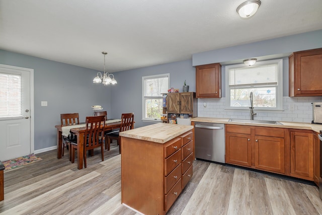 kitchen with stainless steel dishwasher, a sink, healthy amount of natural light, and light wood-type flooring