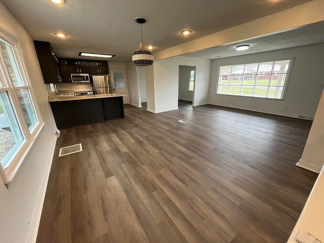 kitchen featuring kitchen peninsula, dark brown cabinetry, dark hardwood / wood-style flooring, and appliances with stainless steel finishes